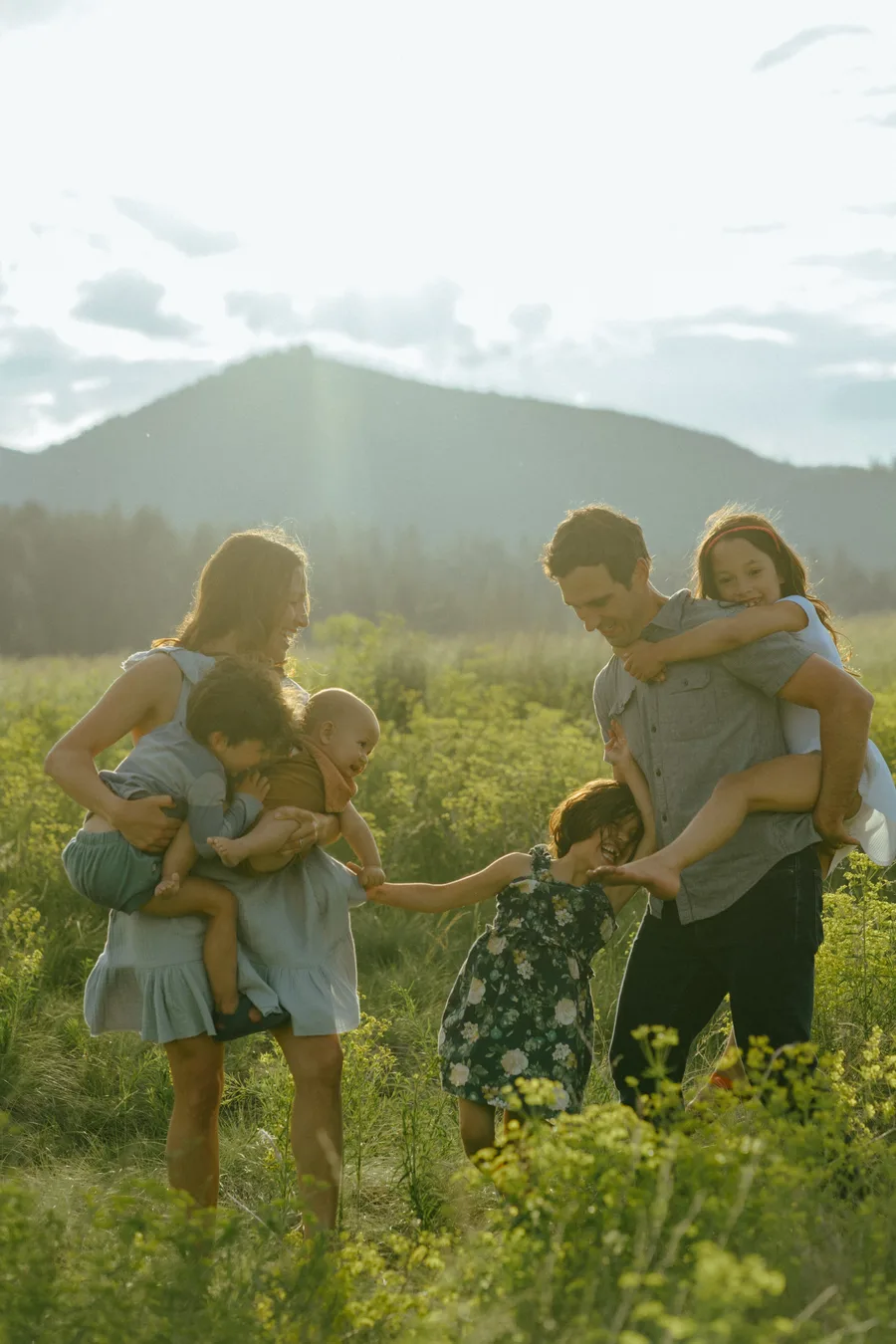 Patrick and his family walking hand-in-hand through a wildflower field with the Montana mountains behind them